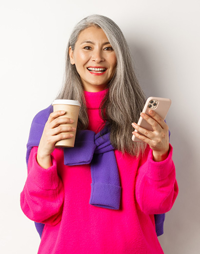 Older woman holding a coffee and a mobile phone